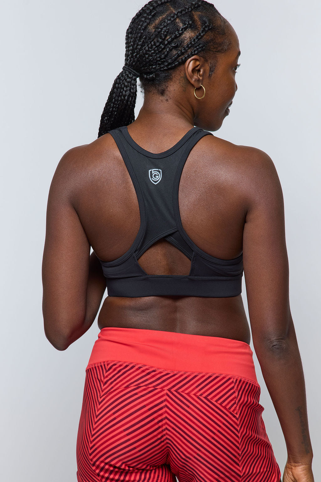 Person wearing a black sports bra and red leggings with a geometric pattern on a plain background