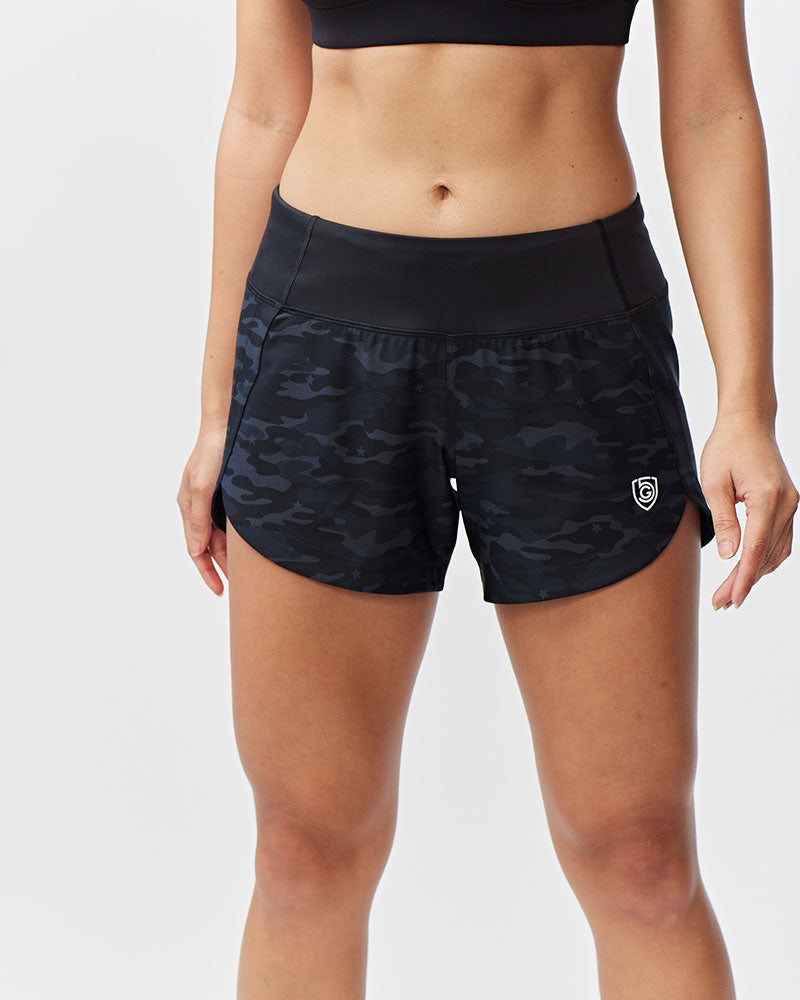 Black camouflage shorts worn by a person on a white background
