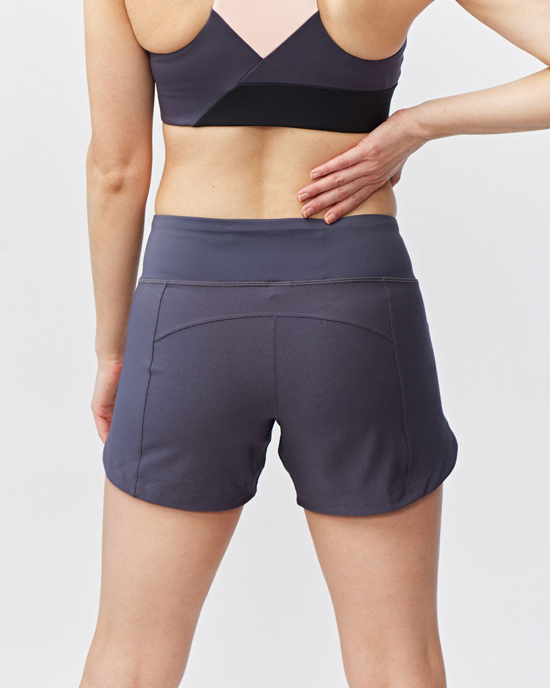 Person wearing a dark sports bra and shorts on a light gray background