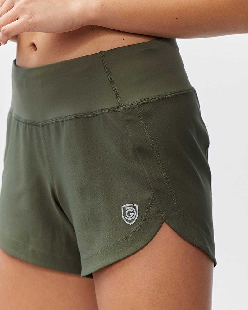 Green athletic shorts with a logo on a neutral background