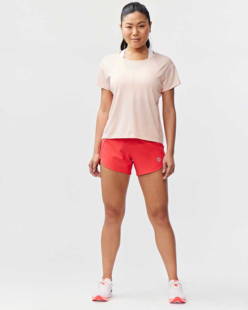Woman wearing a beige t-shirt and red shorts on a white background