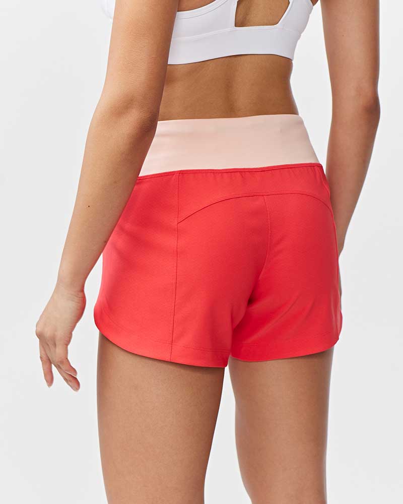 Person wearing red athletic shorts and a white sports bra on a light gray background