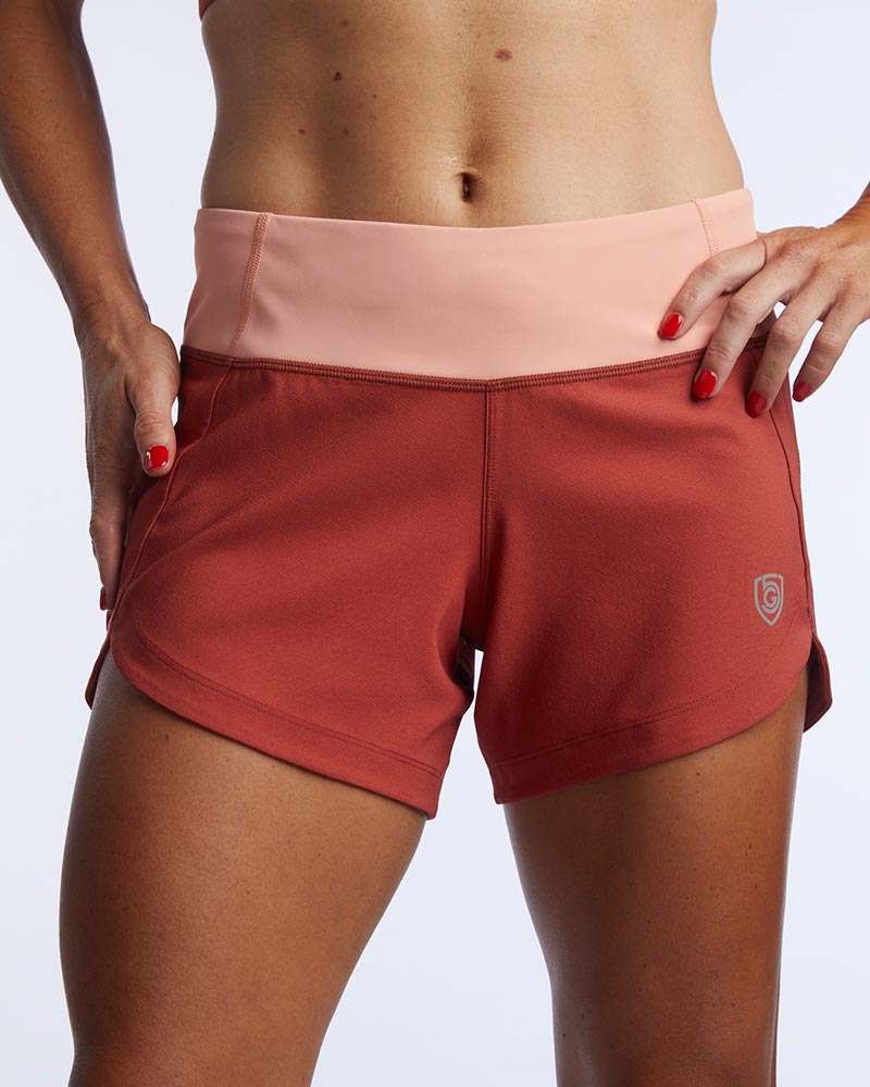 Person wearing red athletic shorts and a pink top on a light gray background
