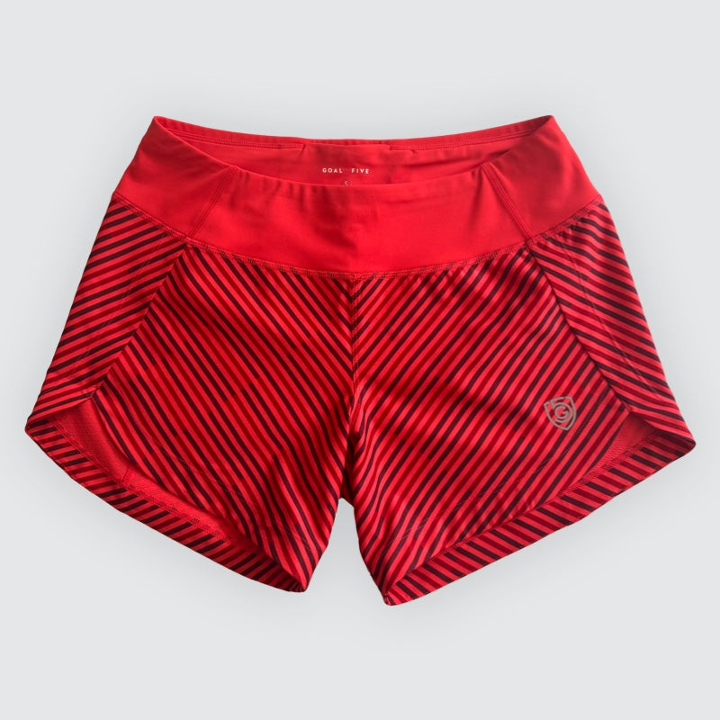 Red athletic shorts with black diagonal stripes on a light gray background